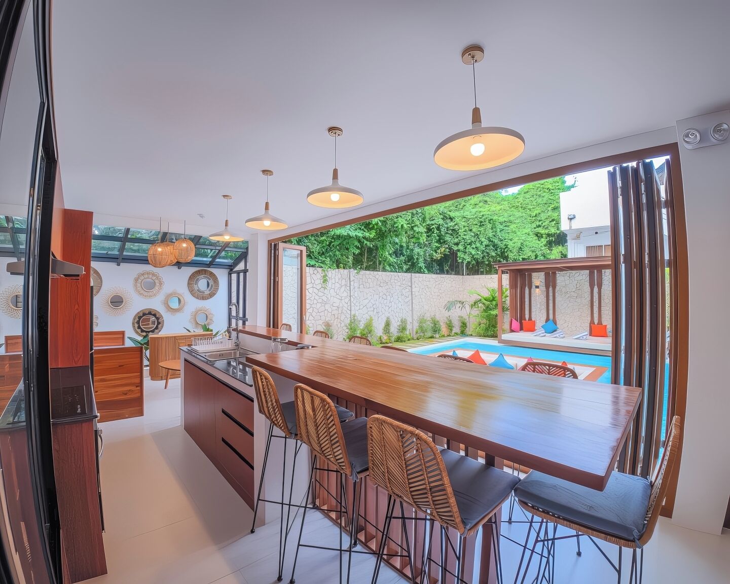 A modern kitchen with a central island, bar stools, pendant lighting, and a view of a swimming pool.