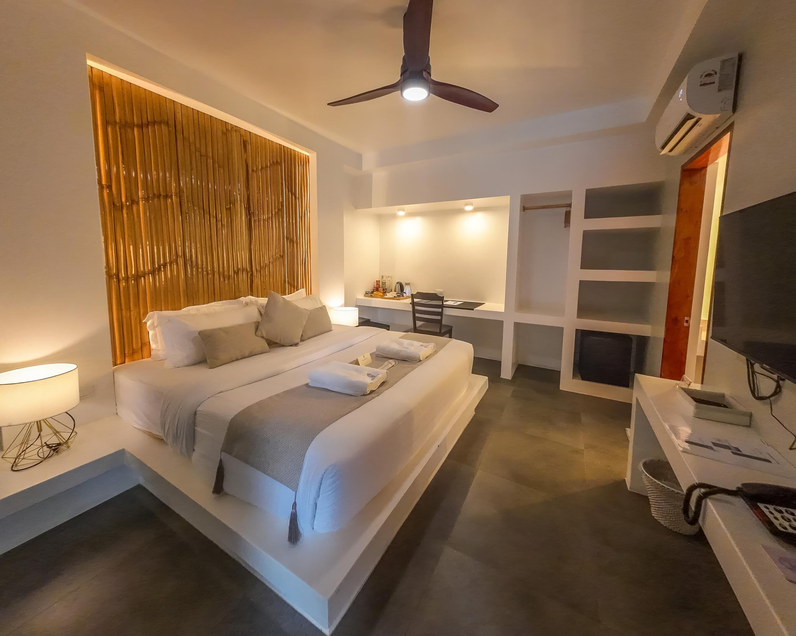 A modern hotel room with a large bed, a desk, and a TV.