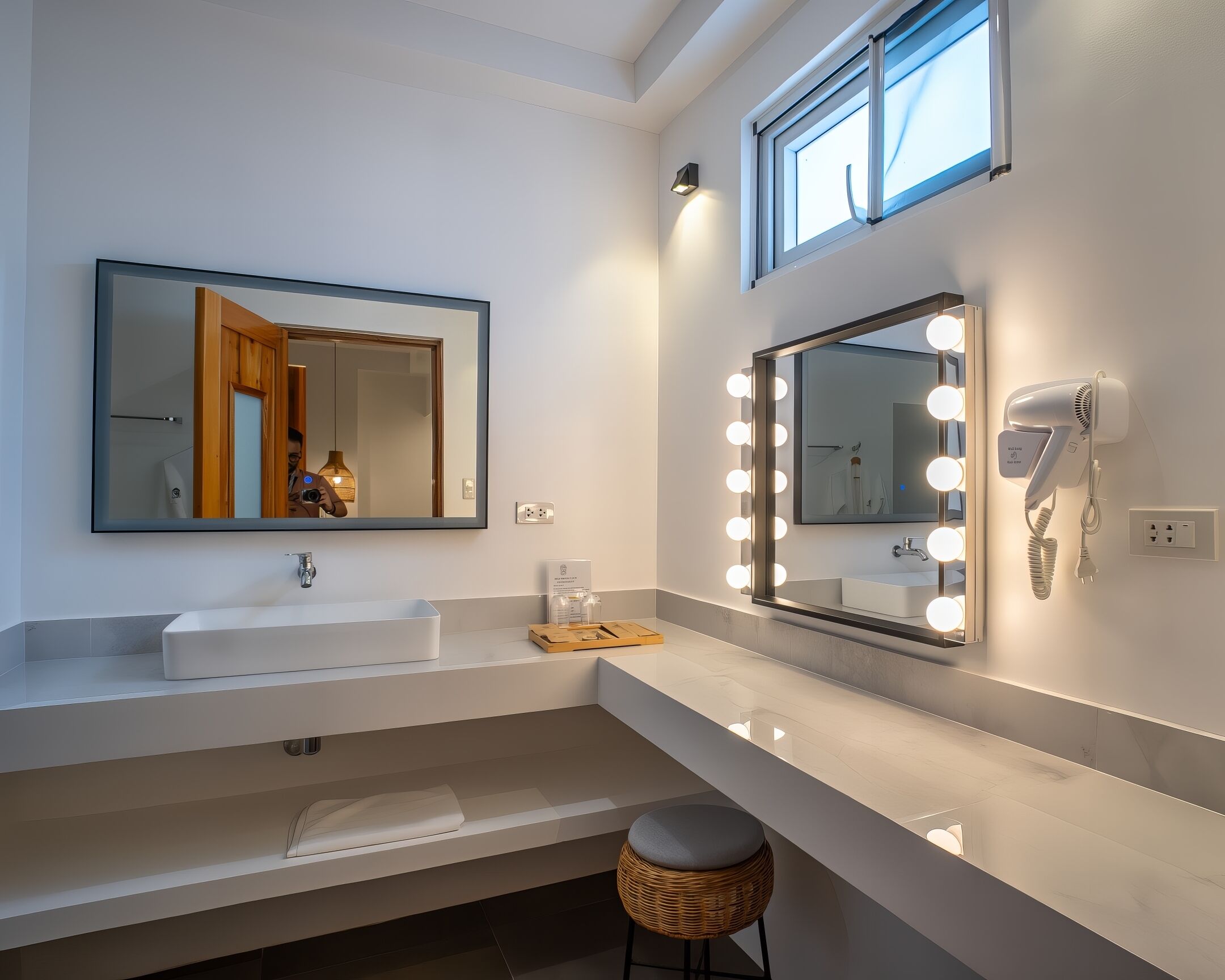 A modern bathroom with a large mirror, vanity, and a hairdryer.