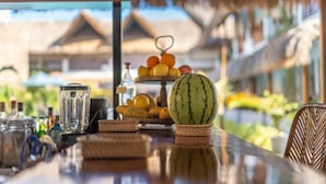 Une table avec une pastèque, un panier de fruits et un mixeur.