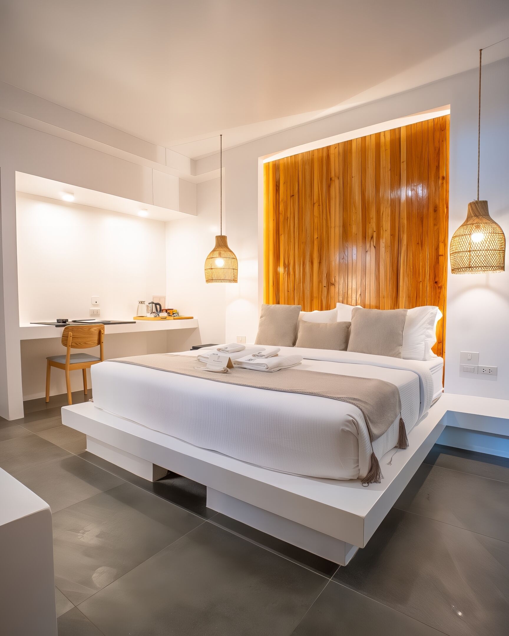A modern bedroom with a large bed, a desk, and two pendant lights.