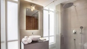 Un baño moderno con ducha de vidrio, un espejo grande y un tocador con lavamanos y toallas.