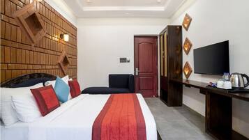 A hotel room with a bed, a TV, a desk, and a wall with a brick pattern.