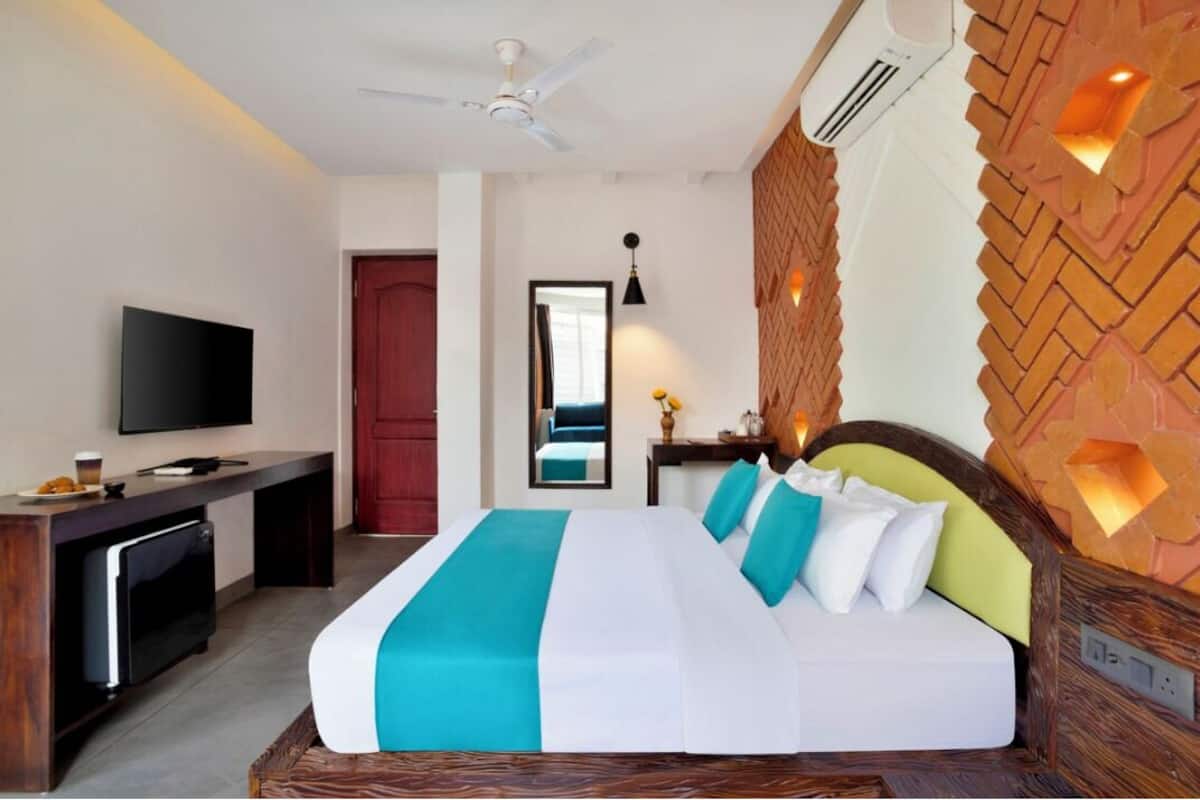 A hotel room with a bed, a desk, a television, and a mirror.
