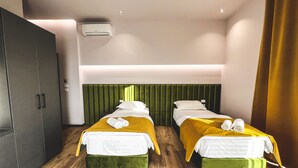 Habitación de hotel con dos camas, un armario y un cabecero verde.