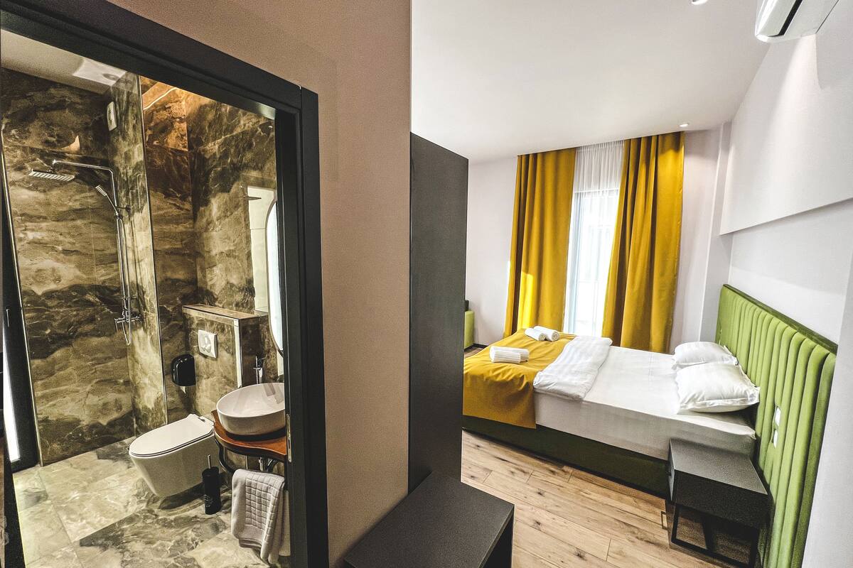 A modern bathroom with a stone shower enclosure, a toilet, and a sink.