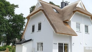 A white house with a unique triangular roof design and a small attached garage.