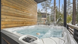 A hot tub with a control panel, wooden walls, and a view of trees and a building in the background. - Diamond Run at Palisades by Tahoe Getaways - Luxury 4BR Townhome, Pet-Friendly, Shuttle & Hot Tub! (Olympic Valley)