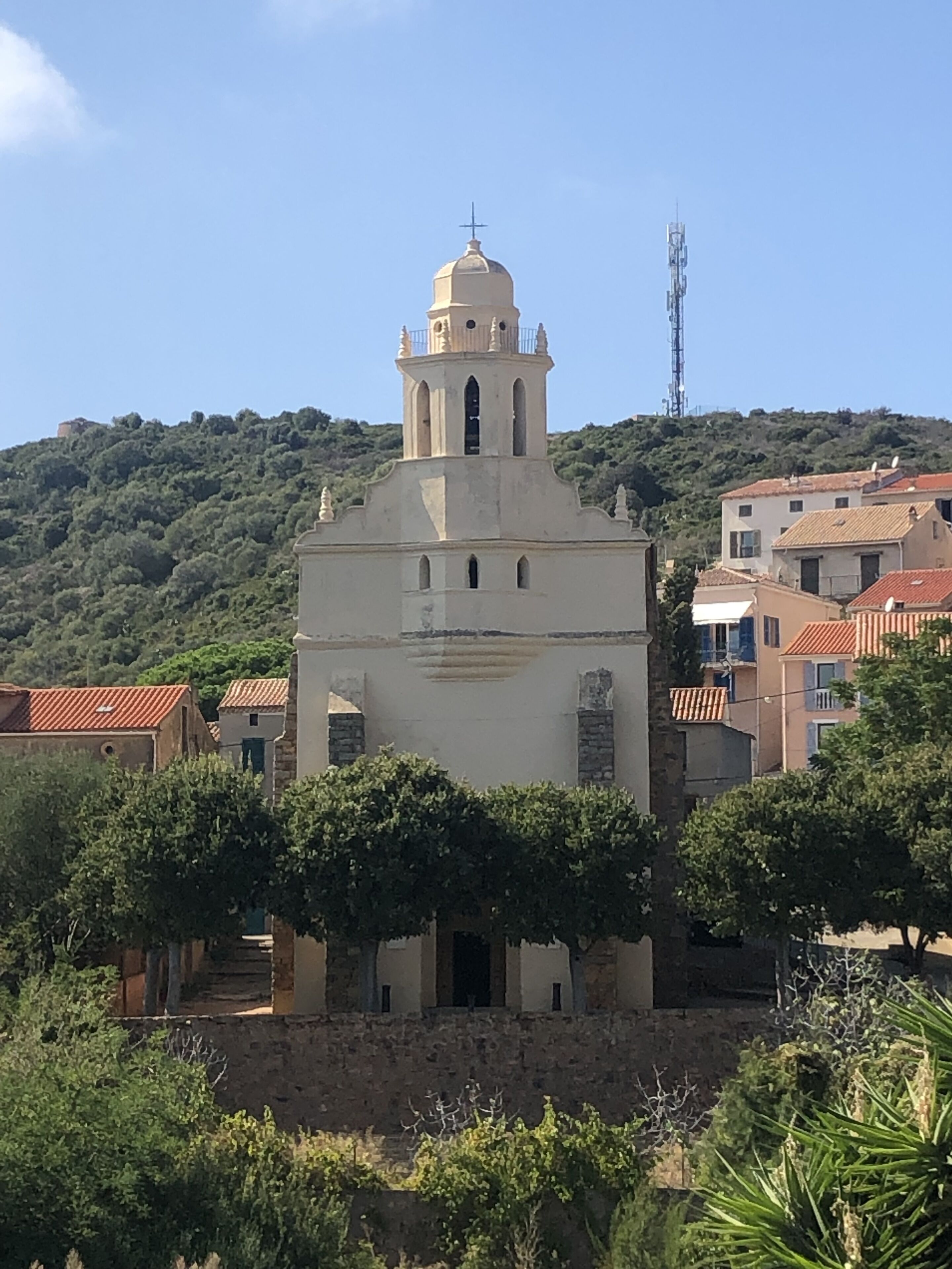 Una iglesia con un campanario, rodeada de edificios y vegetación.