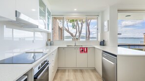 A modern kitchen with a view of the sea, a fire extinguisher, and a dishwasher.