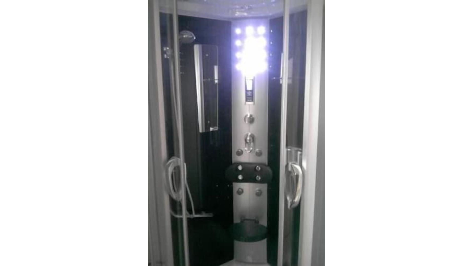 Une petite salle de bain fermée, comprenant des toilettes, un miroir et un espace douche.