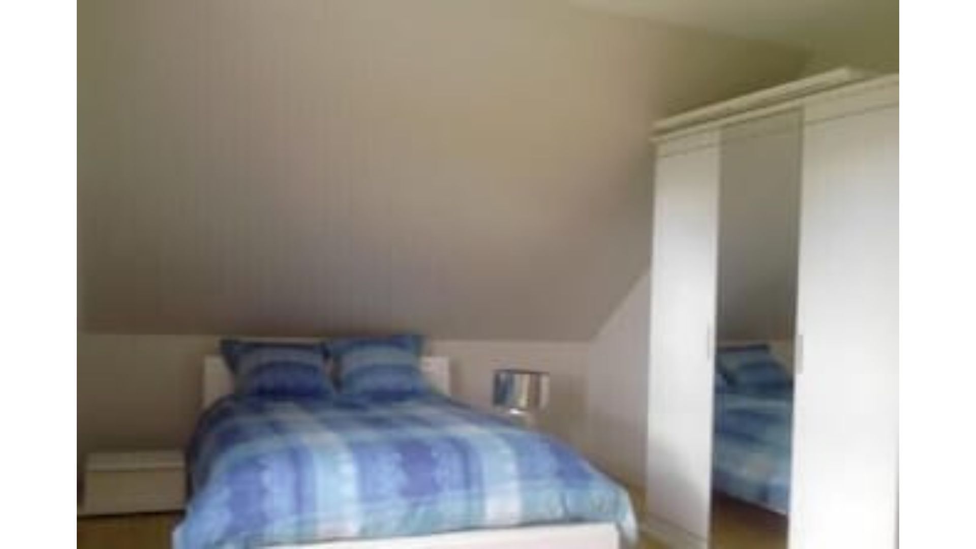 A bedroom with a bed, a nightstand, and a wardrobe.