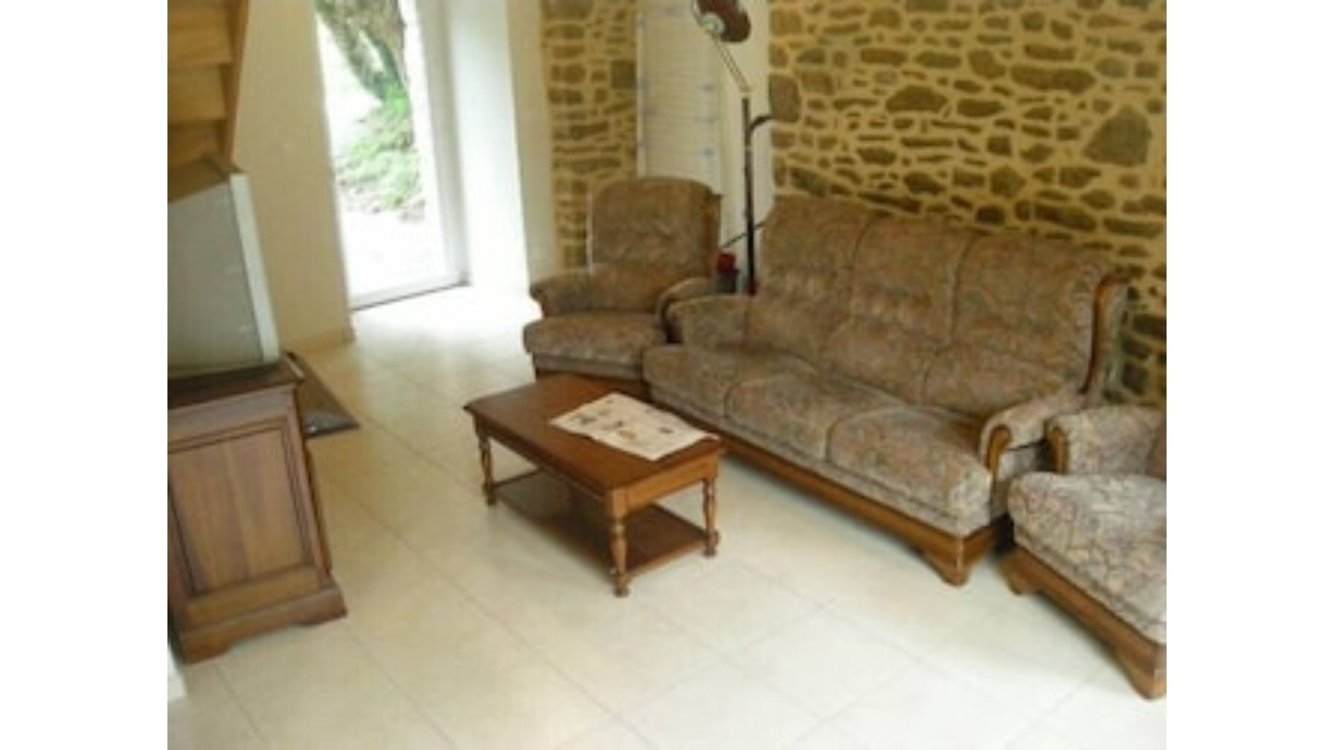 Una sala de estar con una pared de piedra, un sofá, una mesa de centro de madera y una lámpara.