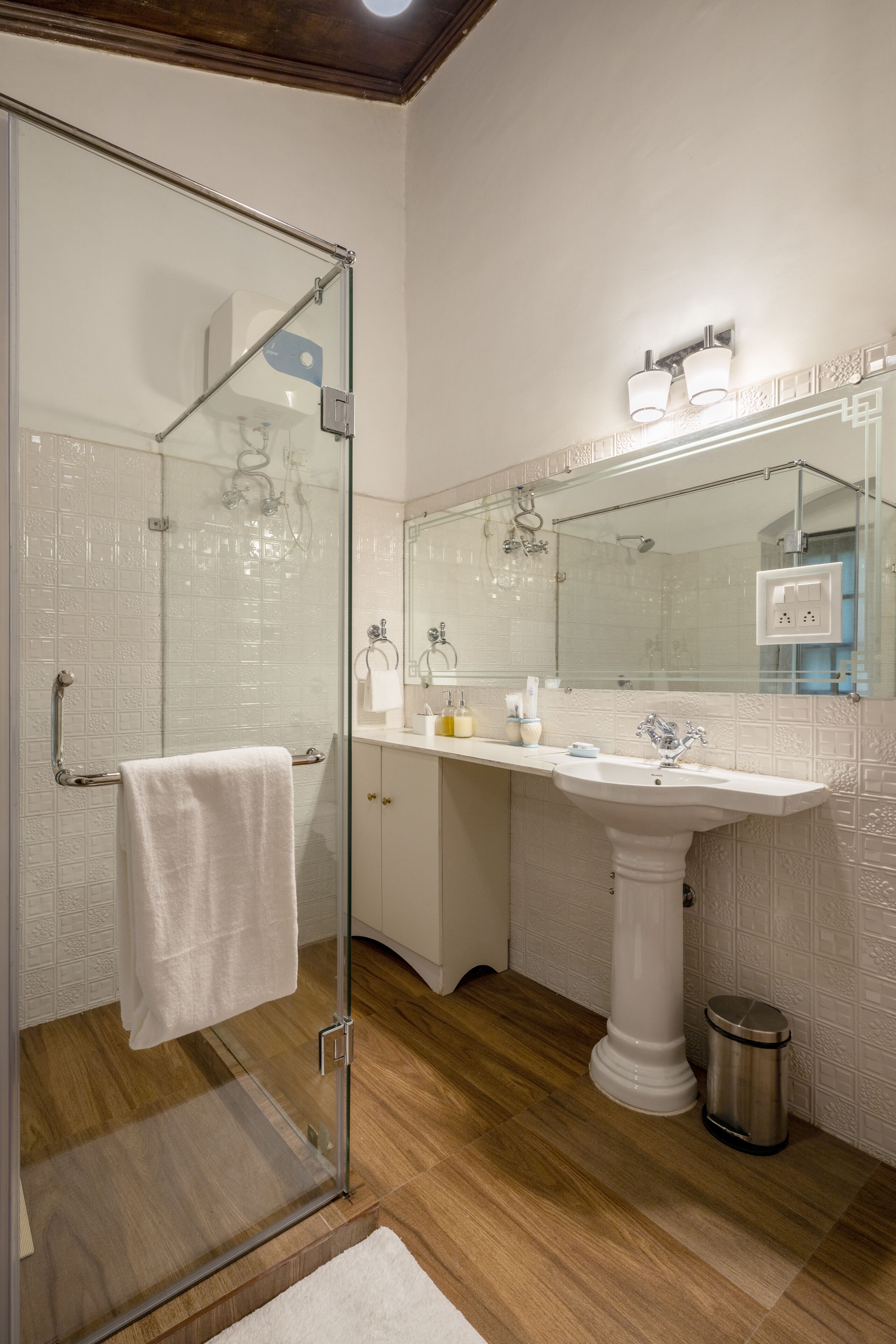 A modern bathroom with a glass shower enclosure, a white sink, and a large mirror.