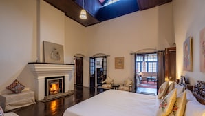 Une chambre spacieuse avec un grand lit, une cheminée et une vue sur le salon.