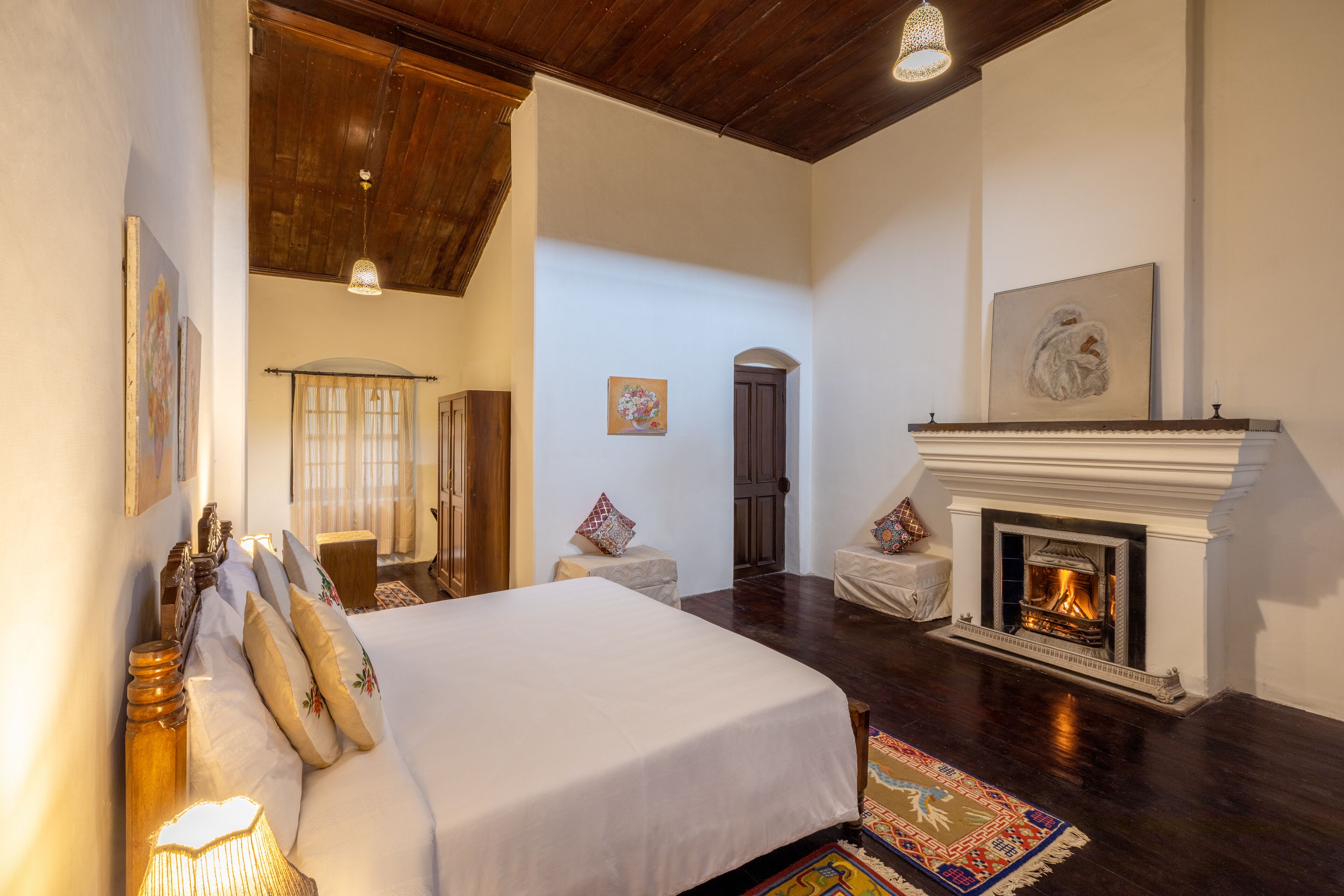 Un dormitorio espacioso con una cama grande, una chimenea y un techo de madera.