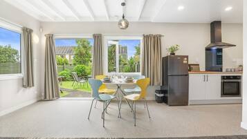 A modern kitchen with a dining area, large windows, and a view of the outdoors.