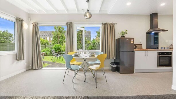 Una cocina moderna con comedor, ventanas amplias y vista al jardín.