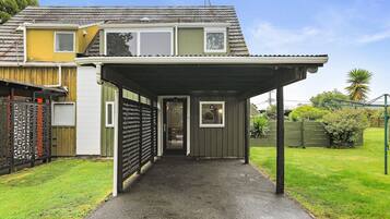 Ein Wohnhaus mit überdachter Auffahrt, umzäuntem Garten und einer kleinen Grünfläche.