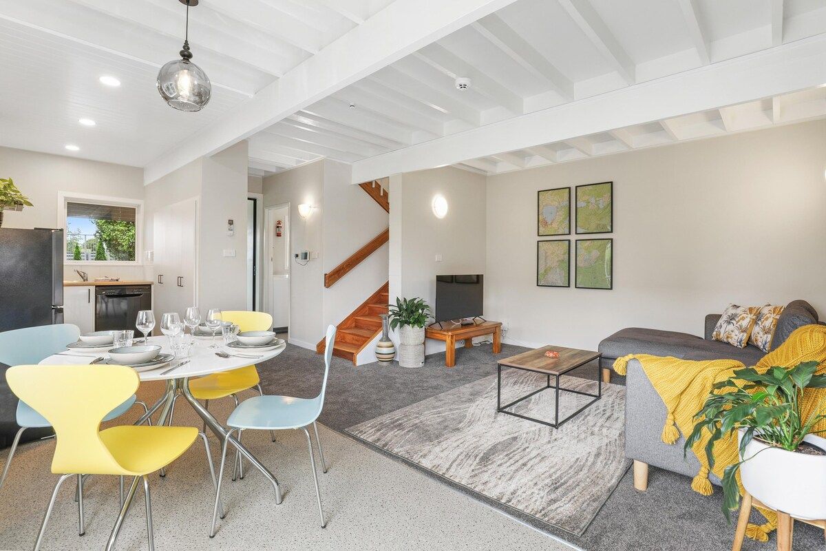 Ein moderner Wohnraum mit Essbereich, einer Couch, einem Couchtisch und einer Treppe.