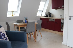 A modern kitchen with red cabinets, a dining table with chairs, and a coffee maker.