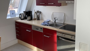 Een moderne keuken met rode kastjes, een ingebouwde oven en een raam met uitzicht.