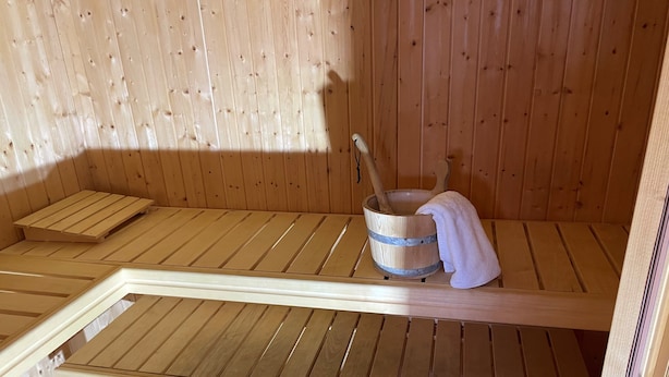 Een sauna met houten banken en een emmer met een handdoek.