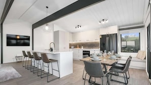 Une cuisine moderne dotée d’un îlot central, de tabourets de bar et d’un coin repas avec une table dressée pour quatre personnes.
