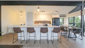 Une cuisine moderne dotée d’un îlot central, de tabourets de bar et d’un coin repas avec une table et des chaises.