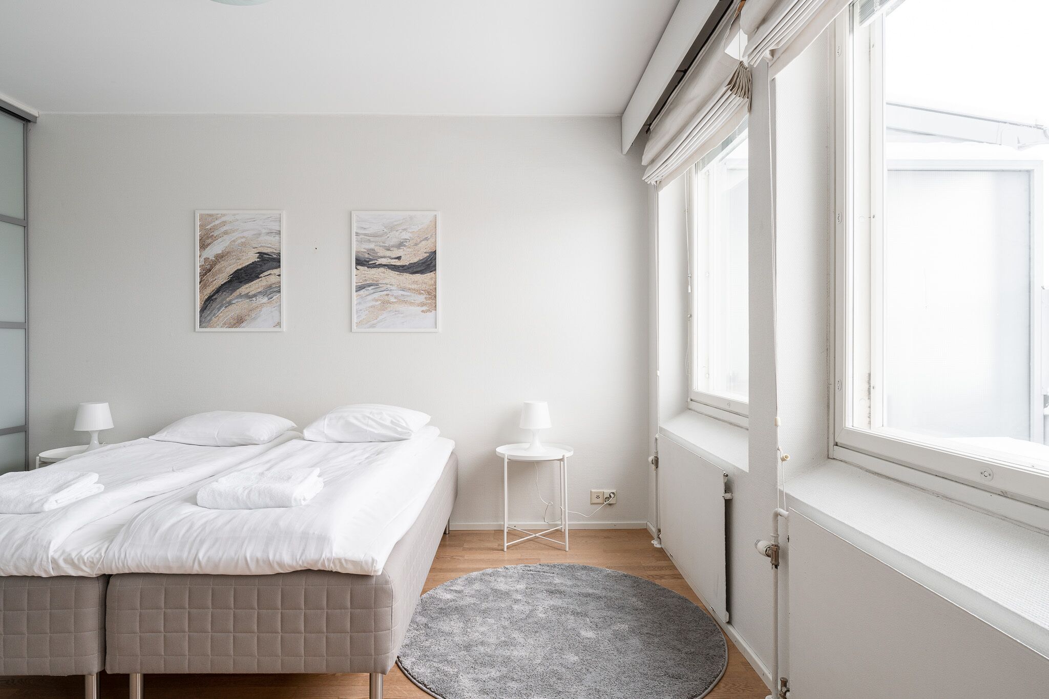 Een slaapkamer met een bed, nachtkastjes, een vloerkleed en kunst aan de muur.