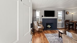 Ein Wohnzimmer mit Kamin, Fernseher und Essbereich mit Tisch und Stühlen.