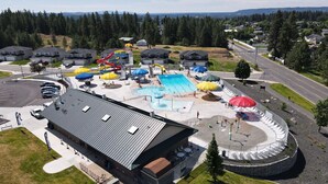 Eine Vogelperspektive eines Resorts mit Schwimmbad, Wasserrutschen und einem überdachten Außenbereich mit Sonnenschirmen.