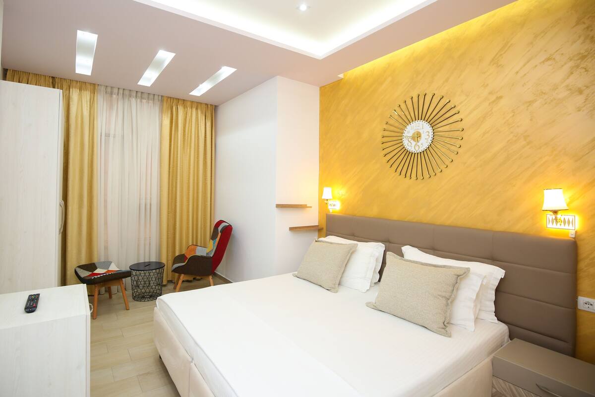 A modern hotel room with a large bed, bedside tables, a desk, and a chair.