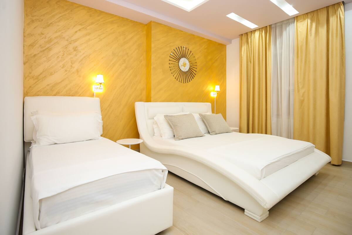 A modern hotel room with two beds, a decorative wall piece, and two bedside lamps.