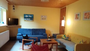 A living room with a blue sofa, a wooden table, and a yellow armchair. - Vacation apartment Schmitt, Abtsteinach, Odenwald, approx. 25 km to Heidelberg (Abtsteinach)