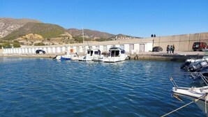 A marina with several boats docked, a concrete wall, and a mountainous backdrop. - Beautiful town house in San Jordi, Castellón (Sant Jordi)