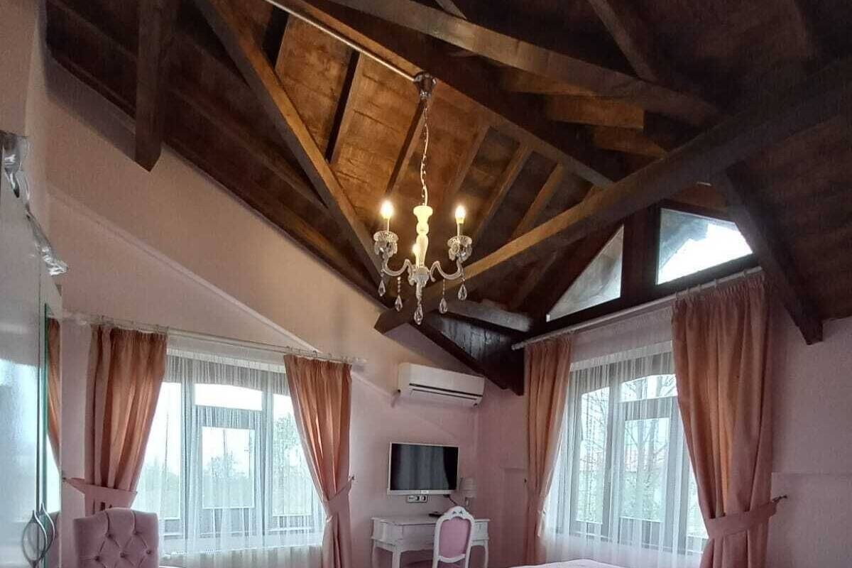 Ein Schlafzimmer mit Holzboden, einem Bett, einem Schreibtisch, einem Stuhl und einem Fernseher.