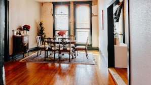 A dining area with a wooden table and chairs, a rug, and a vase with red flowers. - Spacious and Elegant Condo in Downtown Hillsboro (Hillsboro)
