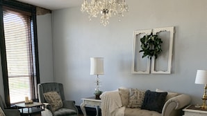 A living room with a chandelier, a sofa, a coffee table, and a rug. - Spacious and Elegant Condo in Downtown Hillsboro (Hillsboro)