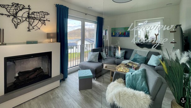 A modern living room with a fireplace, a sofa set, a coffee table, and a world map decoration. - Sonnenweg 36 - LAKEVIEW HOUSE TÜRKIS (Diemelsee)