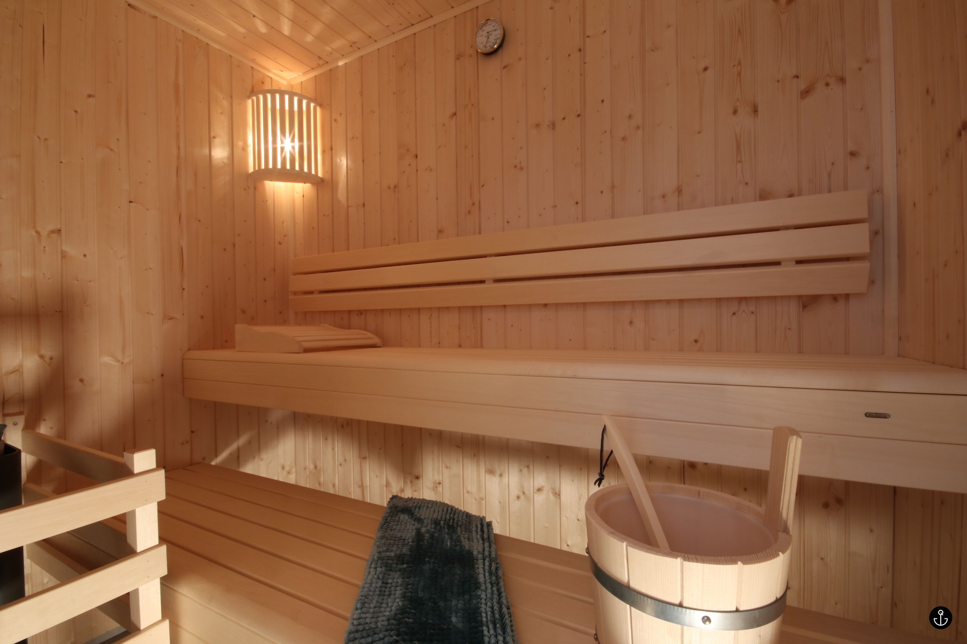A wooden sauna with benches and a bucket.