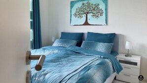 A bedroom with a bed, nightstand, and a painting of a tree. - Sonnenweg 36 - LAKEVIEW HOUSE TÜRKIS (Diemelsee)