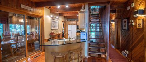 A wooden interior with a kitchen, dining area, and a staircase.