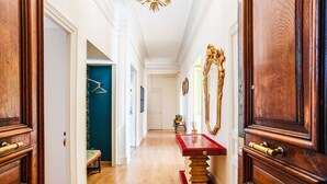 A hallway with wooden doors, a red table, and a mirror.