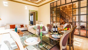 A dining area with a glass table, chairs, and a view of a stone wall and staircase.