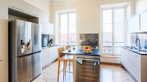 A modern kitchen with a stainless steel refrigerator, a built-in oven, and a dining area with a wooden table and chairs.