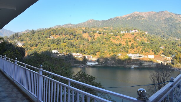 A view from a balcony overlooking a lake with surrounding hills and buildings. - Hotel Lake Paradise Inn (Nainital)