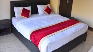 A neatly made bed with a red and white bedspread, a dark headboard, and two pillows. - Hotel Lake Paradise Inn (Nainital)