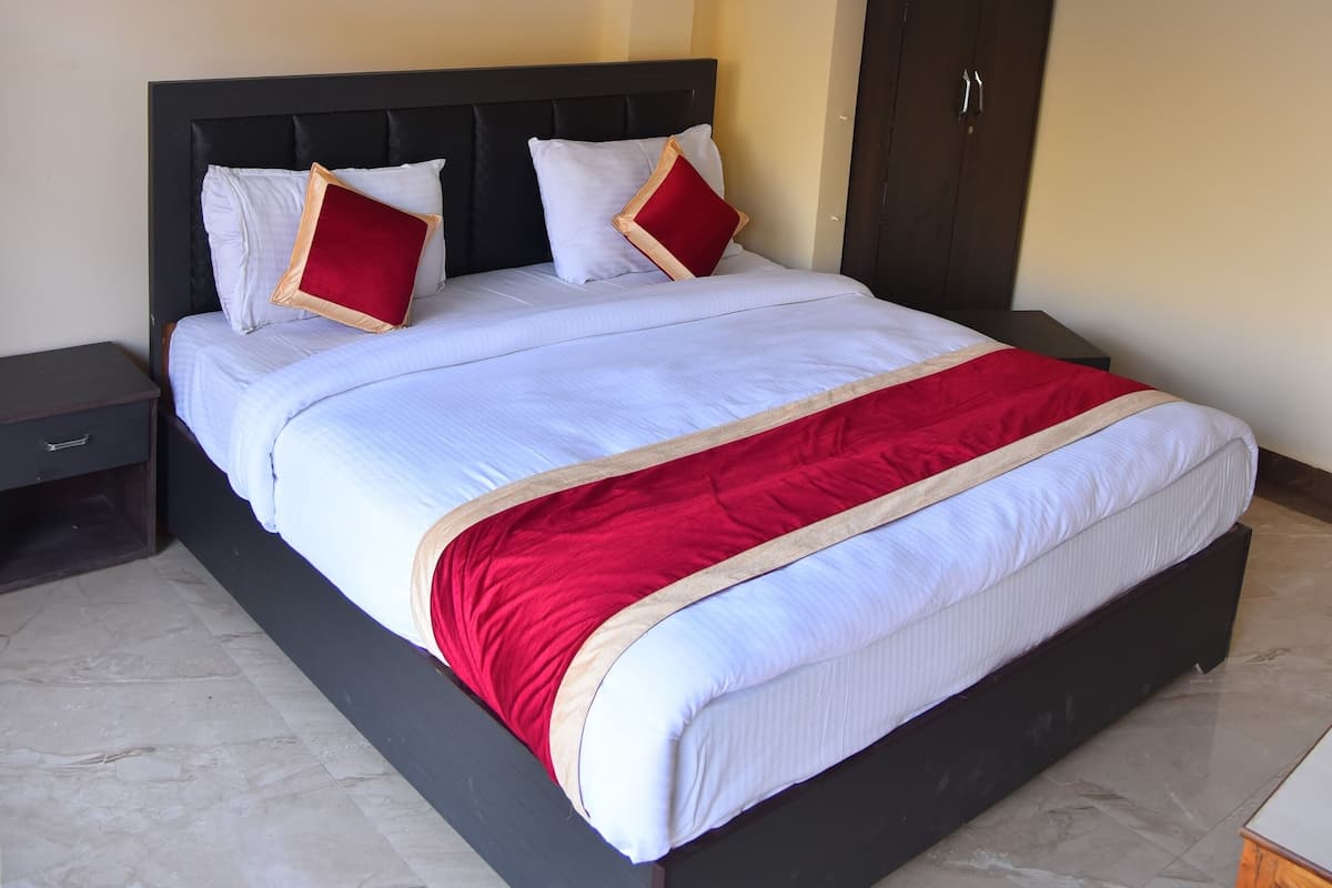 A neatly made bed with a red and white bedspread, a dark headboard, and two pillows.