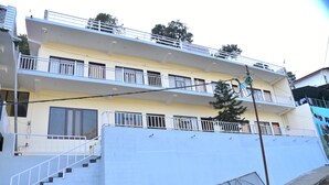 A multi-story building with a white exterior, a balcony on the upper floor, and a staircase leading to the entrance. - Hotel Lake Paradise Inn (Nainital)